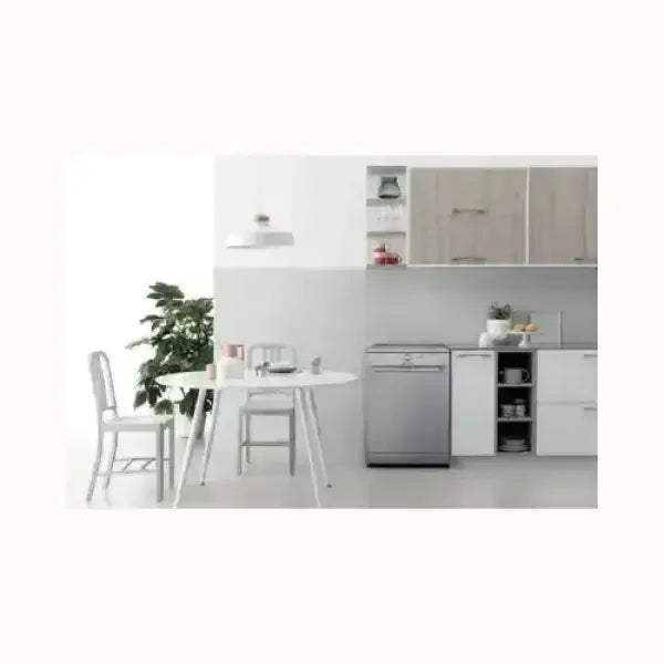 Lavastoviglie INDESIT in cucina moderna accanto a tavolo e sedie bianche con pianta decorativa