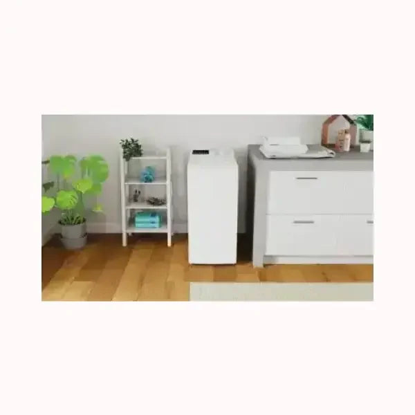 Lavatrice indesit bianca a carica dall'alto collocata in un ambiente domestico con pavimento in legno e mobili bianchi
