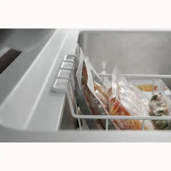 Congelatore a pozzetto Whirlpool aperto con cestello interno e sacchetti sottovuoto contenenti verdure e alimenti